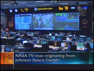 Ora le trasmissioni televisive (e le operazioni spaziali) sono lasciate dal Kennedy Space Center e vengono prese in carico dal Johnson Spce Center di Houston; in fondo alla sala si nota subito il grande schermo che mostra i dati delle operazioni in corso dello space shuttle in orbita, la sua posizione rispetto alla superficie terrestre e le immagini che giungono da esso:  KB